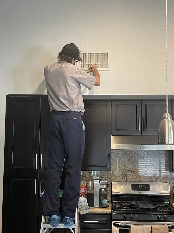 Technician inspecting an air vent during HVAC service in Fairmont